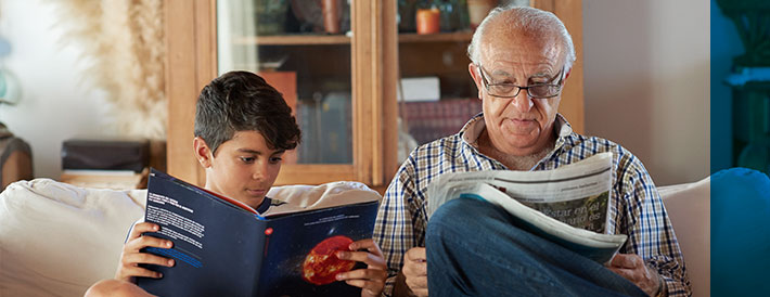 Grandfather and grandson reading book sitting on the couch